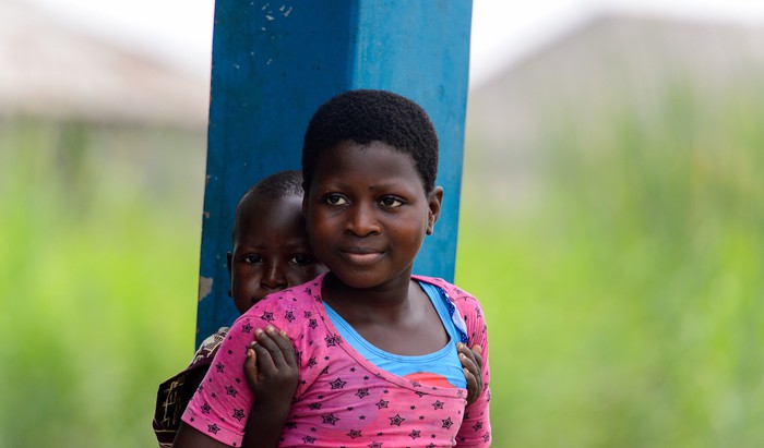 Beninese girl carries her sister in a village over the lake Nokwe