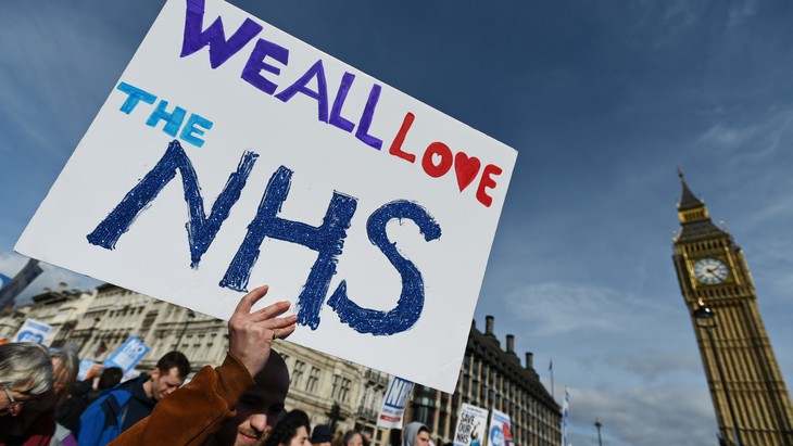 Protesters march past Parliament during a demonstration in support of the NHS